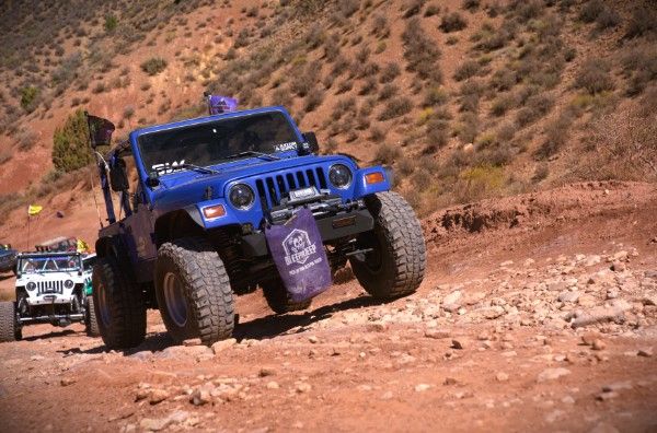Betty Lou, a blue 1997 Jeep Wrangler, crawling over loose rock on a red-dirt trail with another Jeep behind it